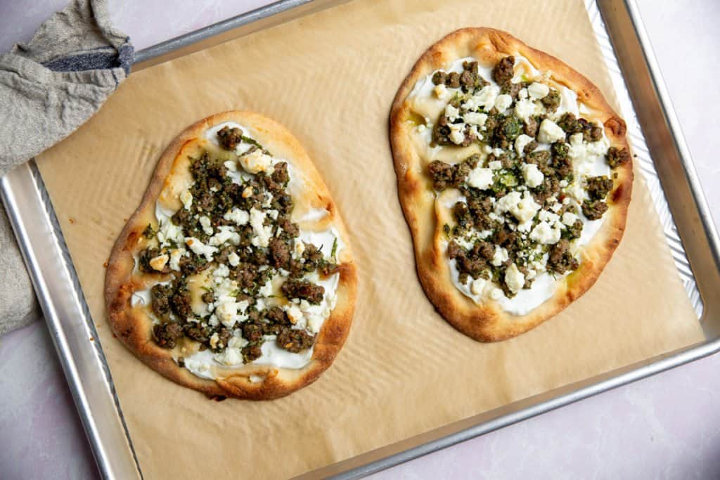 The cooked lamb flatbreads on a parchment lined baking sheet.