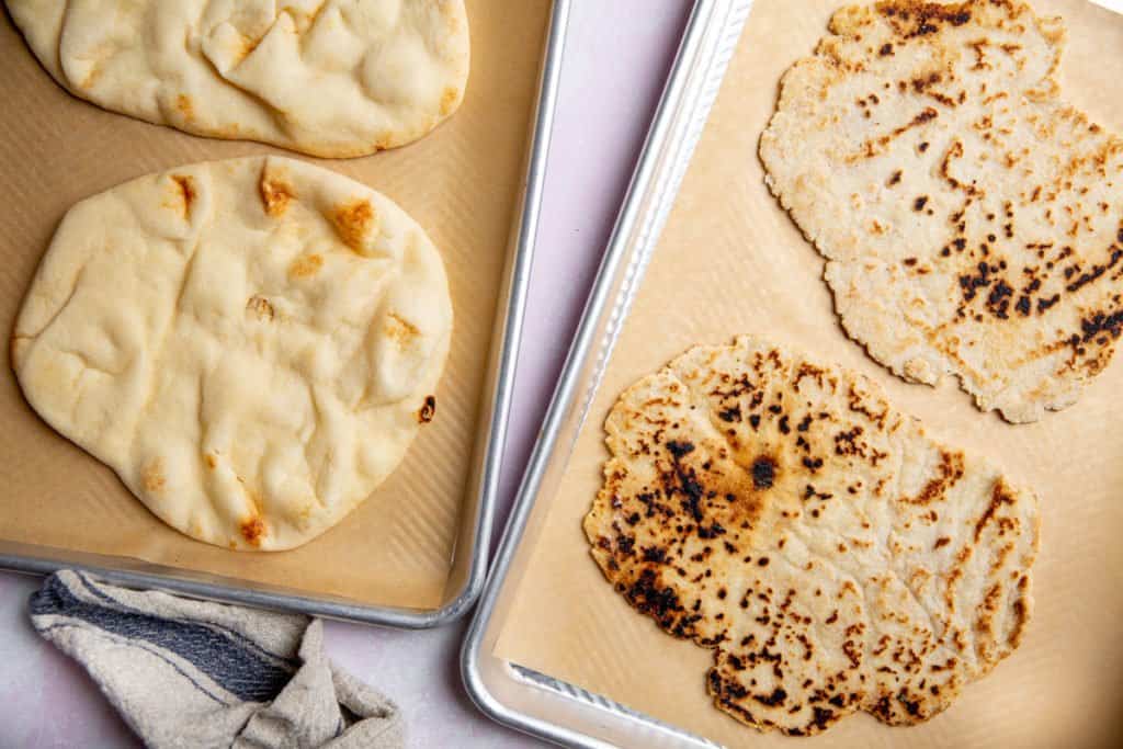 Naan flatbreads and gluten free flatbreads on parchment lined baking sheets. 
