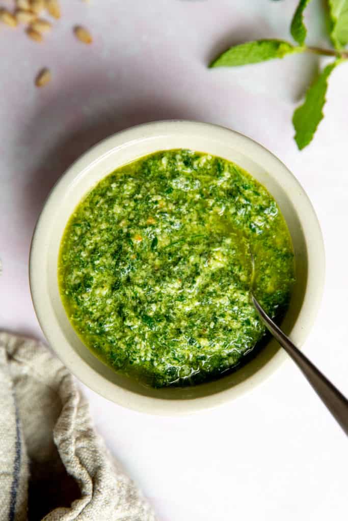 Close-up of a bowl of mint pesto with a spoon. 