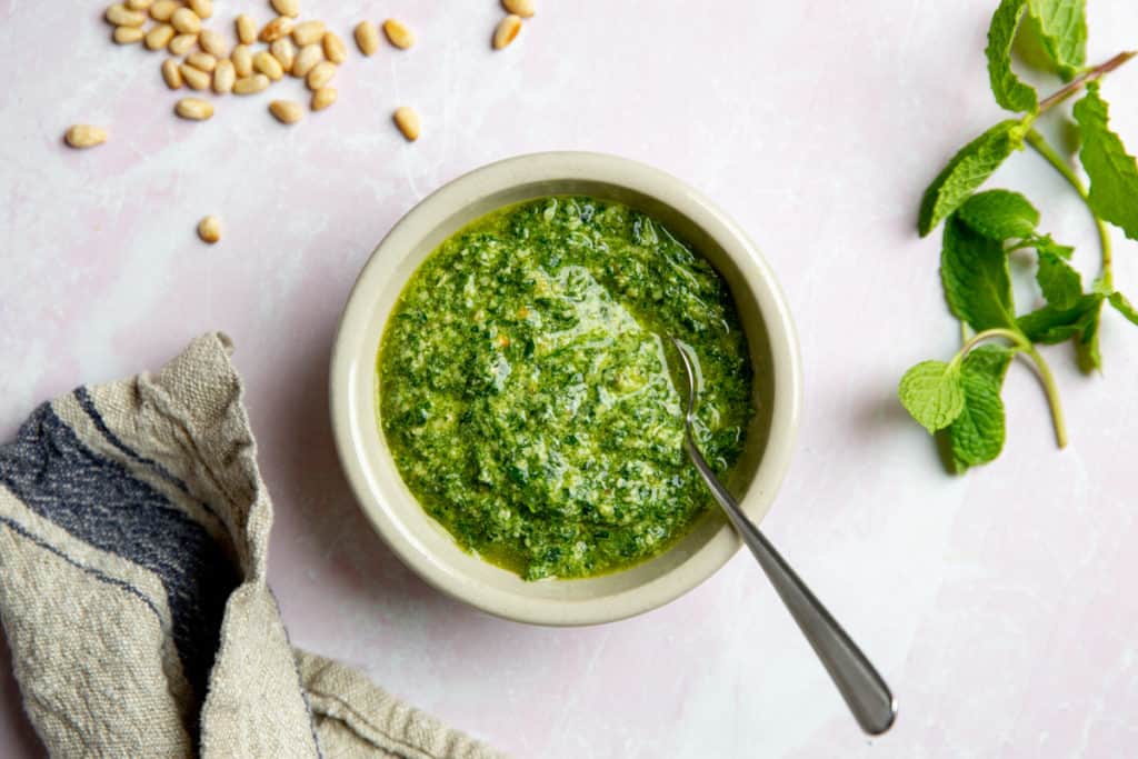 A bowl of mint pesto with a spoon. 