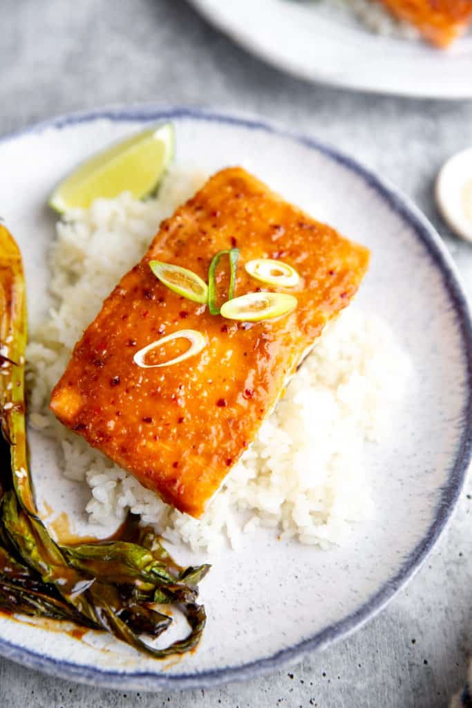A fillet of miso glazed salmon over rice with baby bok choy on the side.