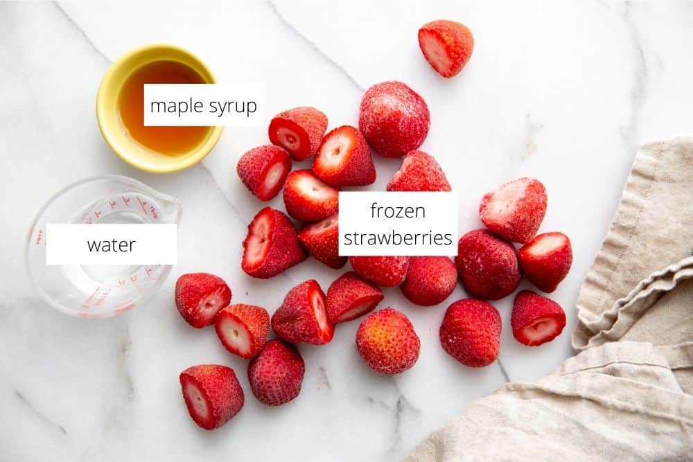 The ingredients for the strawberry sauce recipe on a marble surface with labels. 