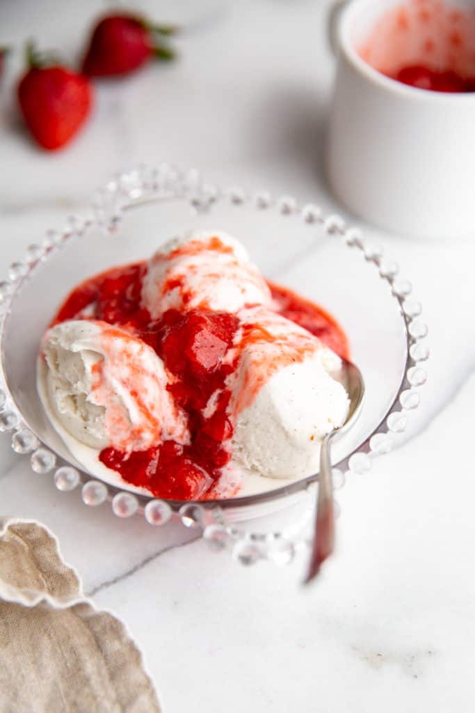 A bowl of ice cream with a strawberry sauce topping. 