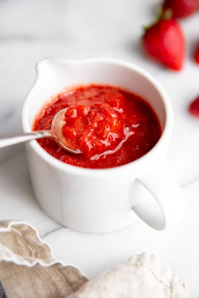 Close-up of a bowl of strawberry compote with a spoon. 