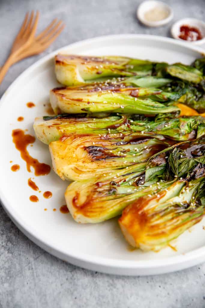 Cooked bok choy on a plate drizzled with hoisin glaze.