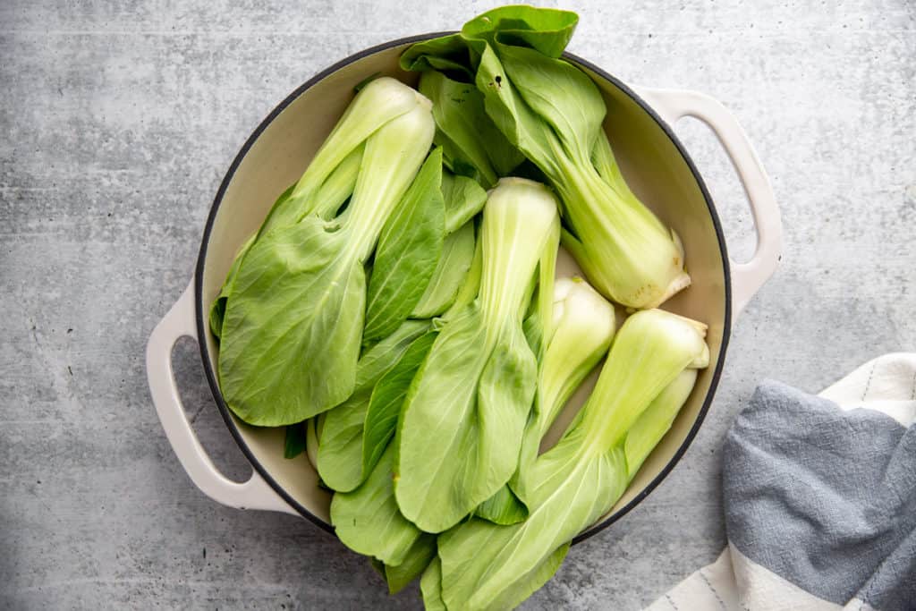 Process shot showing baby bok choy arranged in a hot skillet 