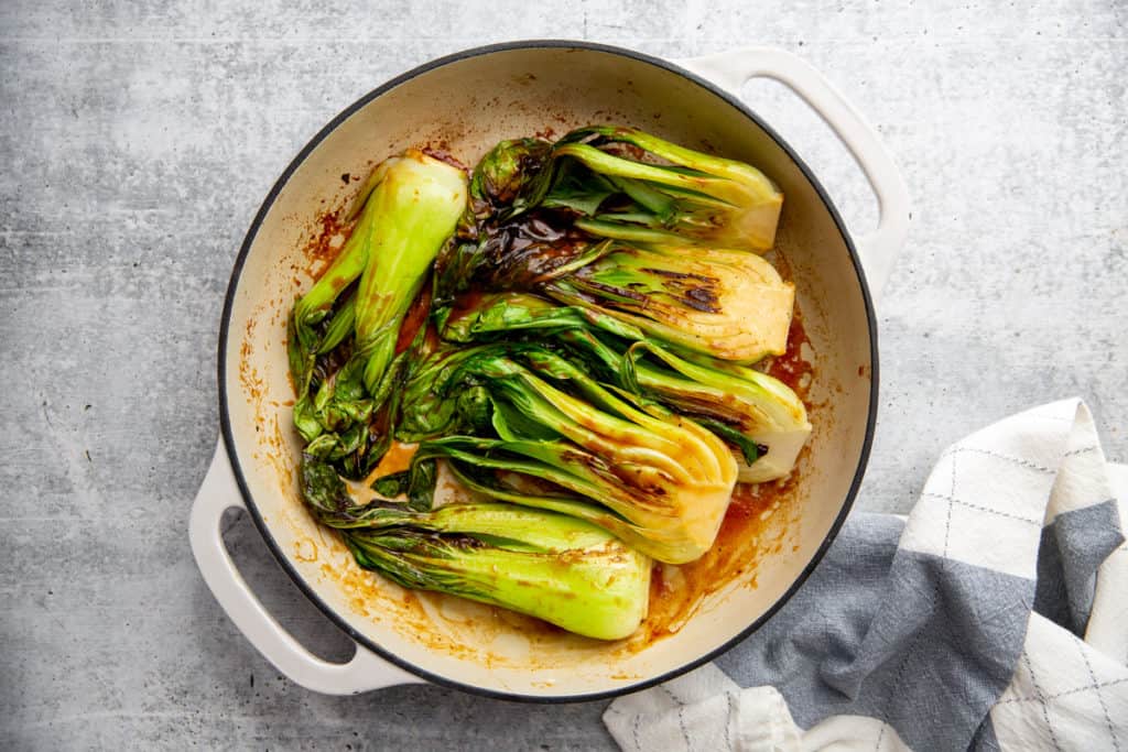 The cooked hoisin glazed baby bok choy in a skillet.