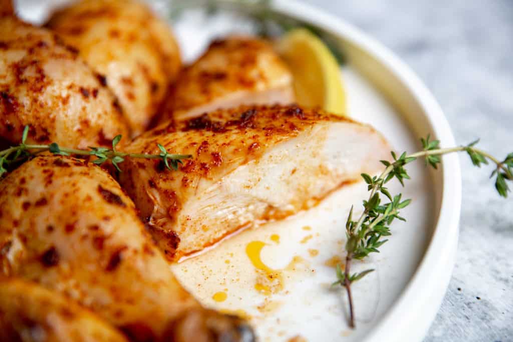 Smoked Chicken on a plate with lemon slices and garnishes.
