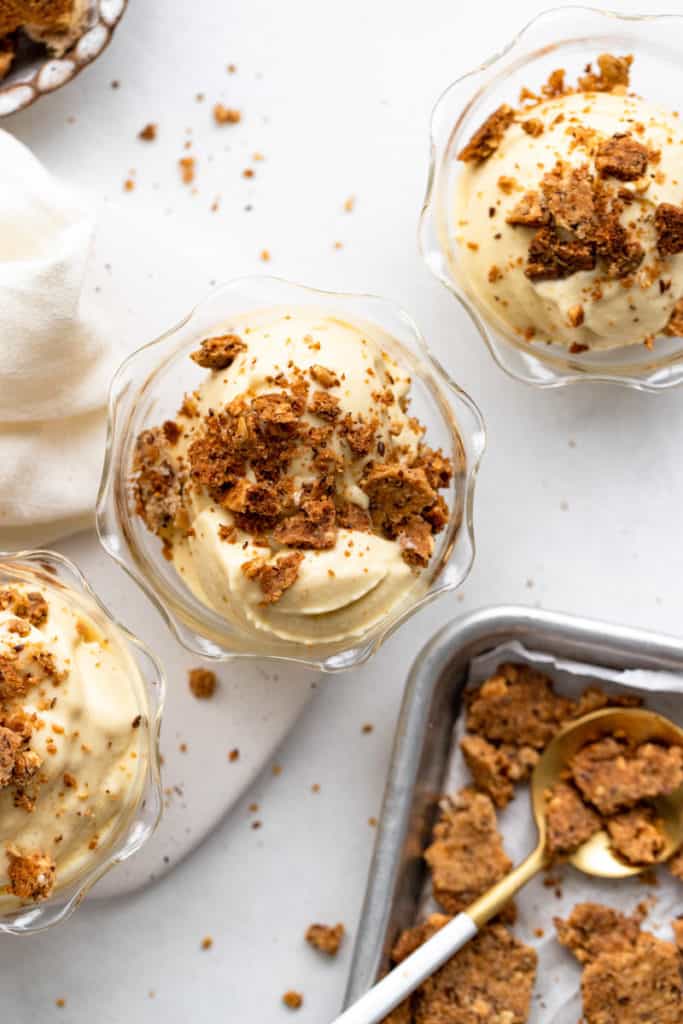 Vegan mango ice cream in serving glasses, topped with coconut peanut crumble.