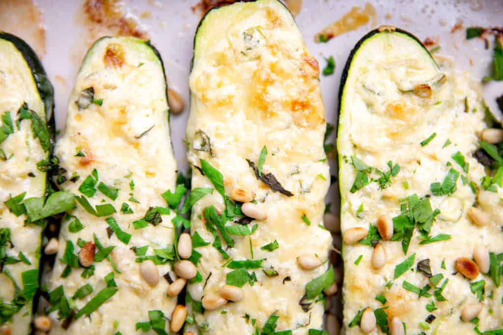 Baked stuffed zucchini with herbs and nuts on top.