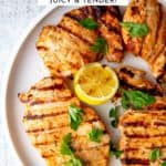Yogurt marinated grilled chicken on a platter with grilled lemon halves.