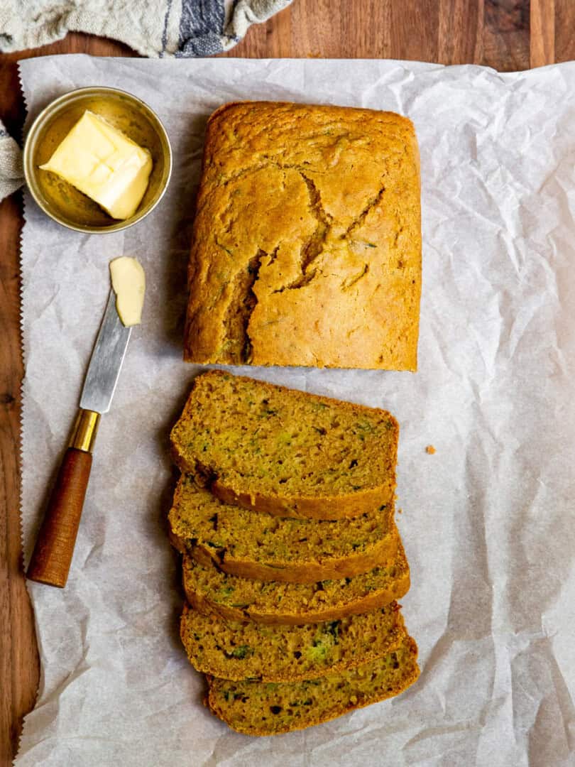 Gluten free zucchini bread half sliced on top of a chopping board.