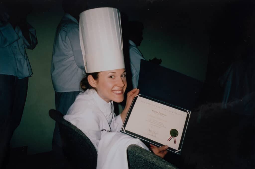 Nicki Sizemore in culinary school holding her Degree in Culinary Arts.