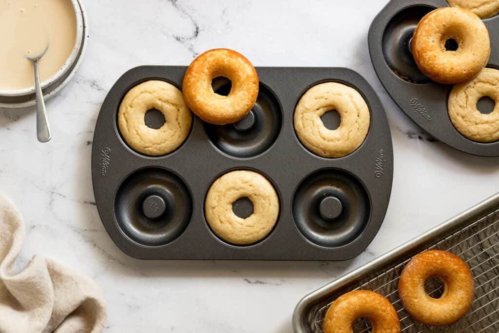 Baked gluten free donuts on top of baking screen and donut cups.