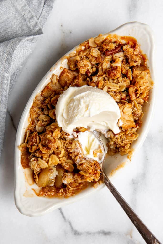 Close-up of a healthy, gluten free apple crisp in a serving dish topped with ice cream. 