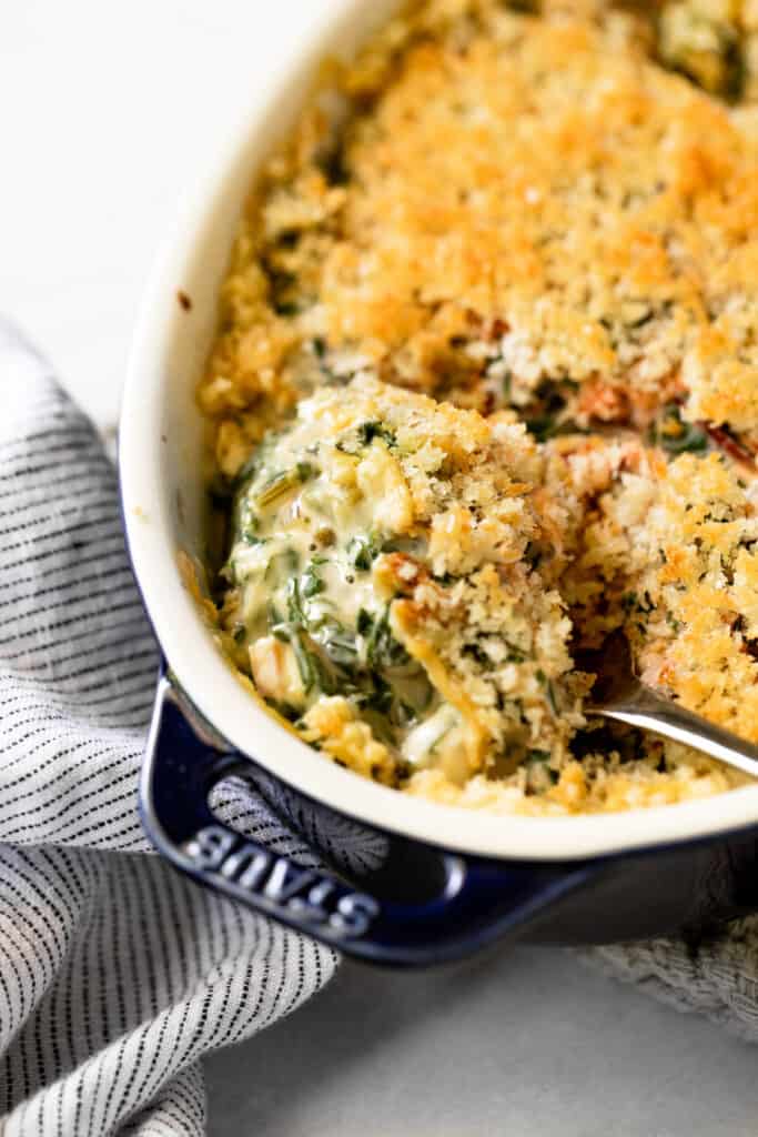 Close-up of a spoonful of Swiss chard gratin in a baking dish.