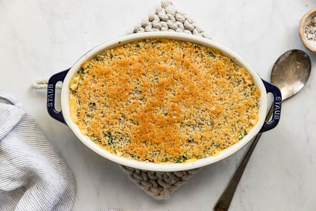The baked gratin in a serving dish with a spoon alongside.