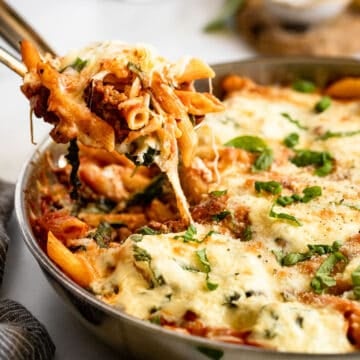Close up of a spoonful of baked pasta with sausage and ricotta.