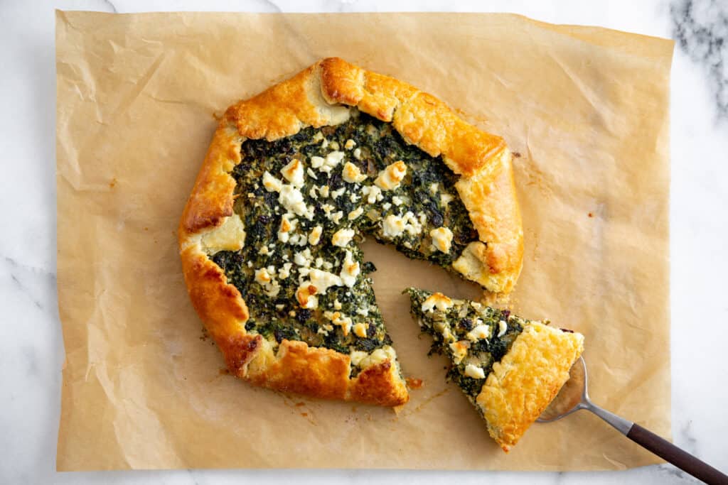 A savory gluten-free spinach tart on a piece of parchment paper. 