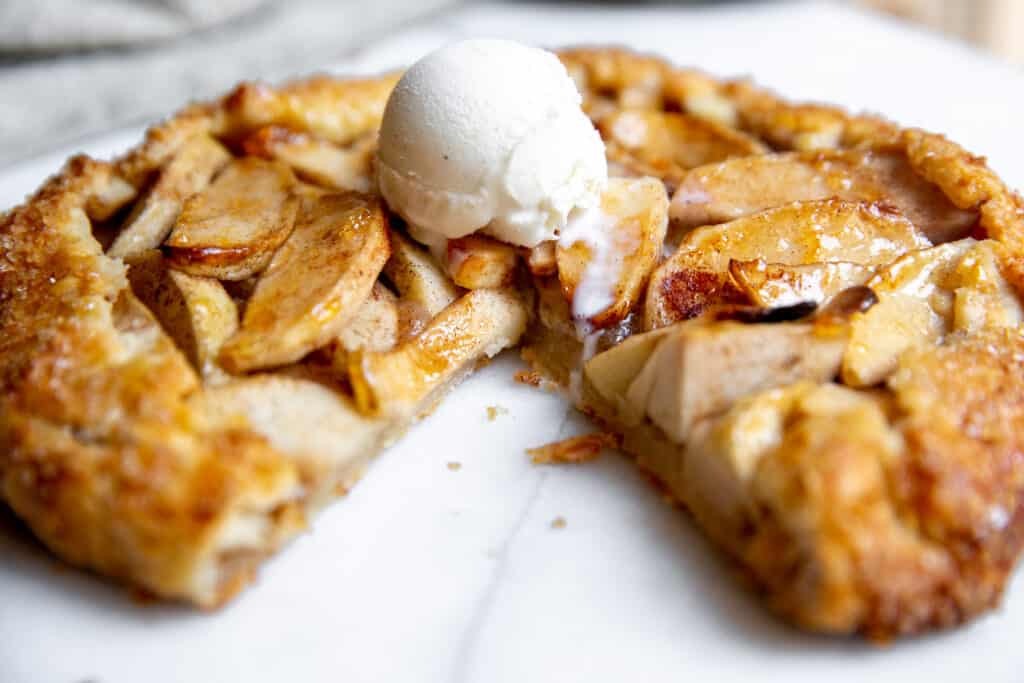 Close up of a gluten free apple galette topped with vanilla ice cream. 