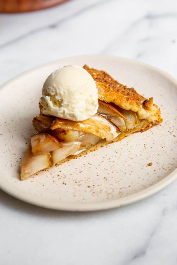 A piece of apple pie topped with vanilla ice cream. 
