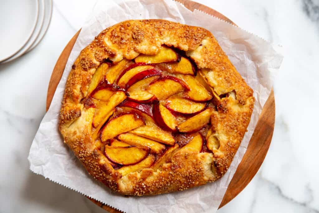 A gluten free peach galette on a cake stand.