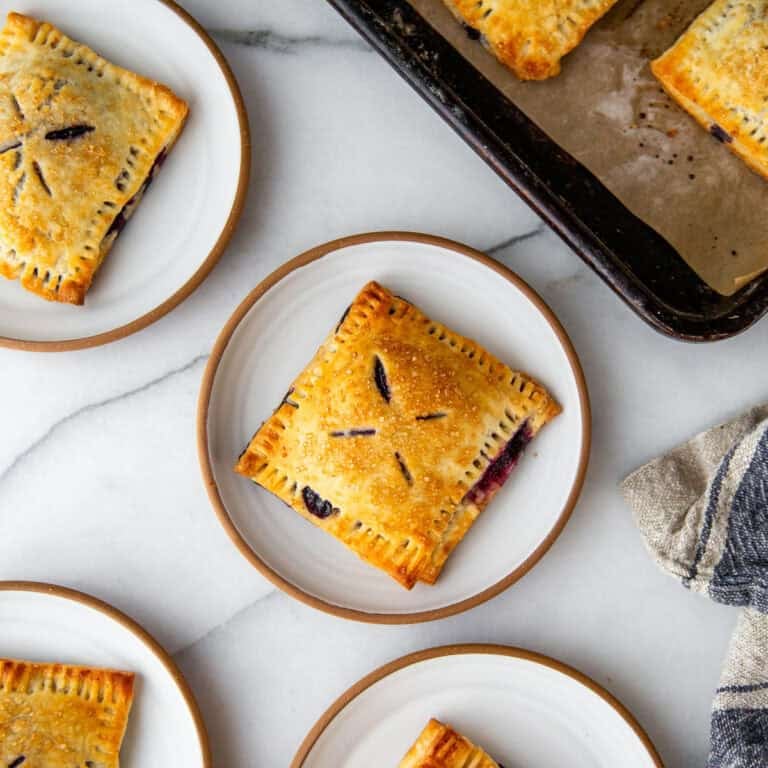 four blueberry hand pies on a individual white plates