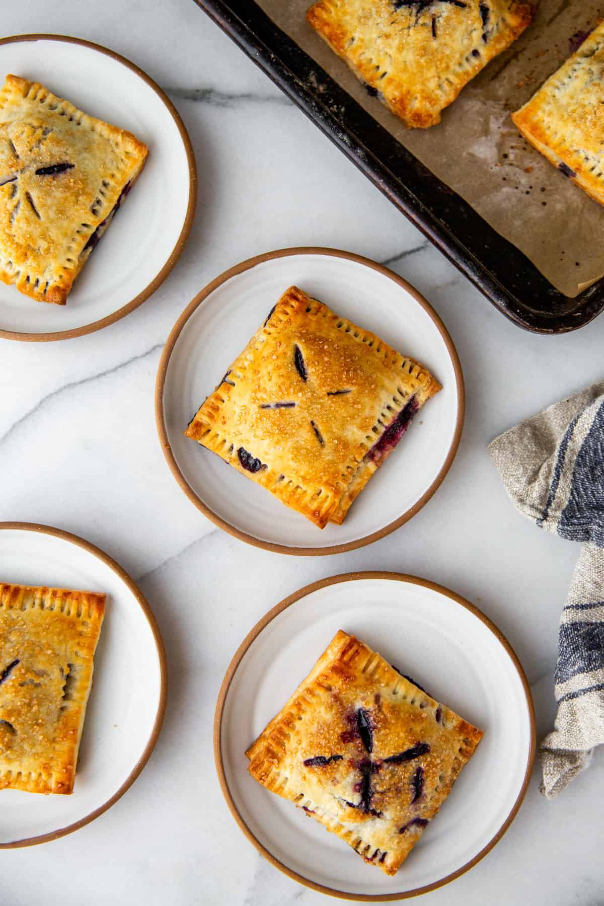 four blueberry hand pies on individual plates