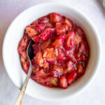 roasted rhubarb in a white bowl with a spoon resting on the side