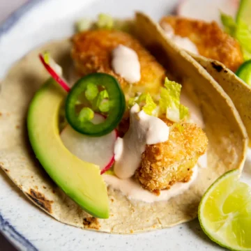 crispy fish tacos on a plate with a lime wedge