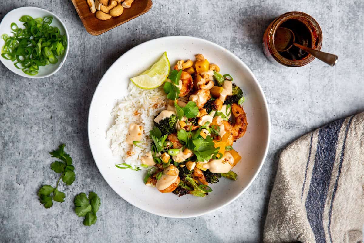 chili crisp shrimp atop rice and veggies in a white bowl