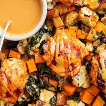 an overhead shot of gochujang chicken on a sheet pan with a bowl of sauce in the middle