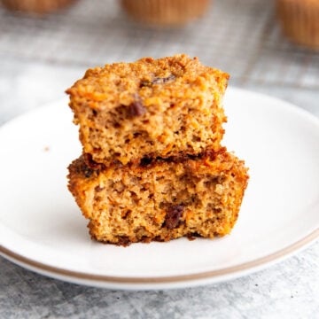 two halves of a carrot raisin muffin stacked on a white plate