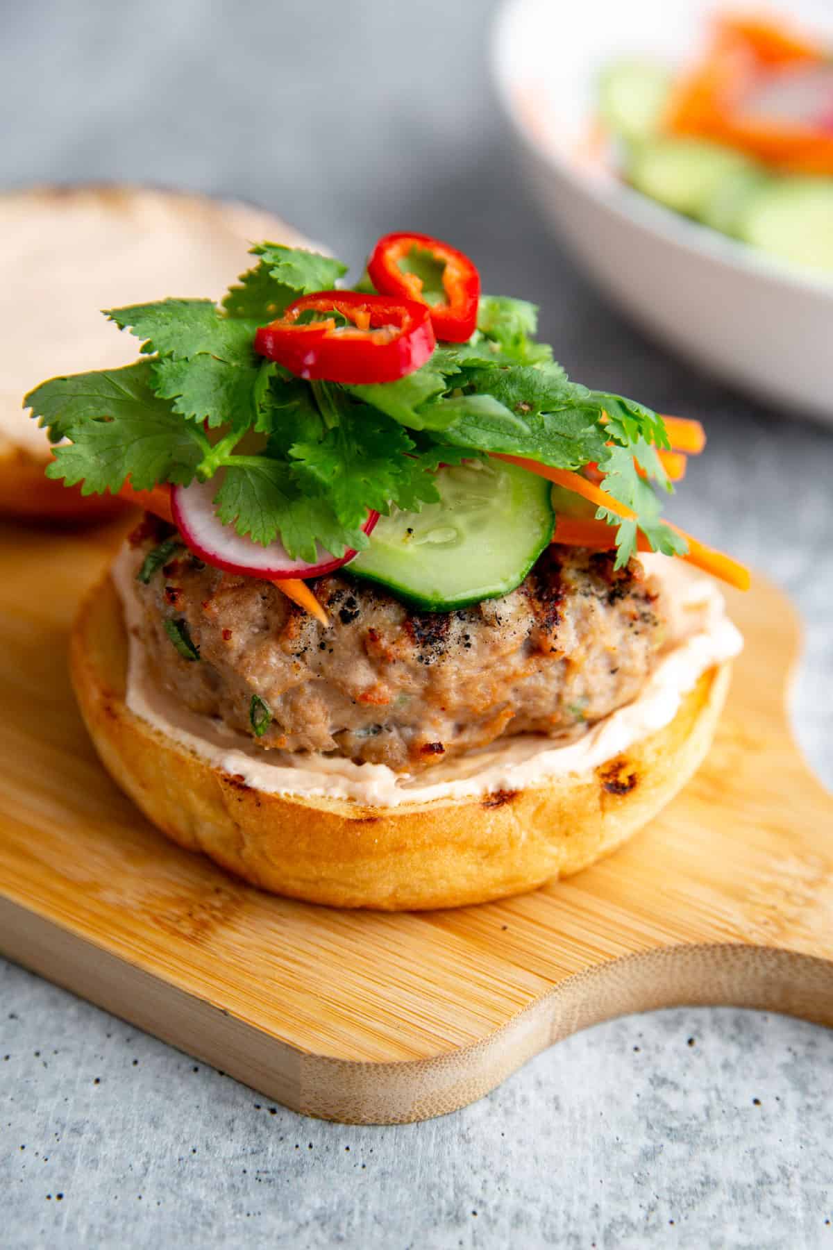 a banh mi burger without the top bun piled will pickled veggies and fresh herbs