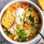 a bowl of creamy white bean soup topped with sour cream and cornbread.