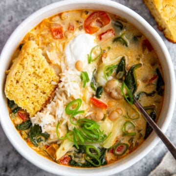 a bowl of creamy white bean soup topped with sour cream and cornbread.