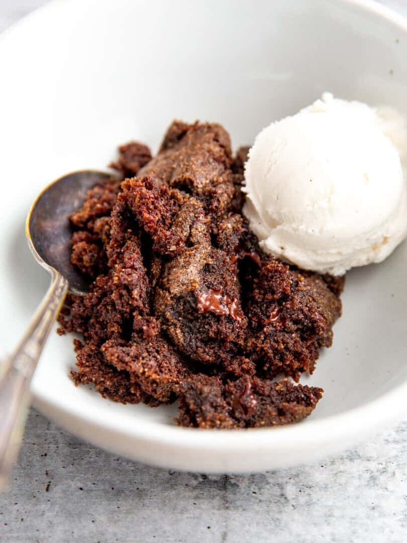 double chocolate spoon cake topped with vanilla ice cream in a white bowl