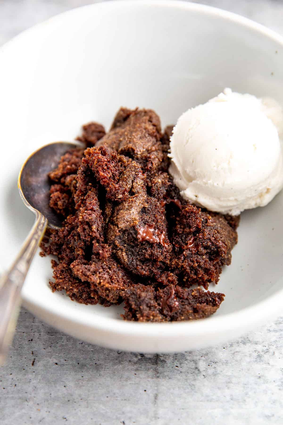 double chocolate spoon cake topped with vanilla ice cream in a white bowl
