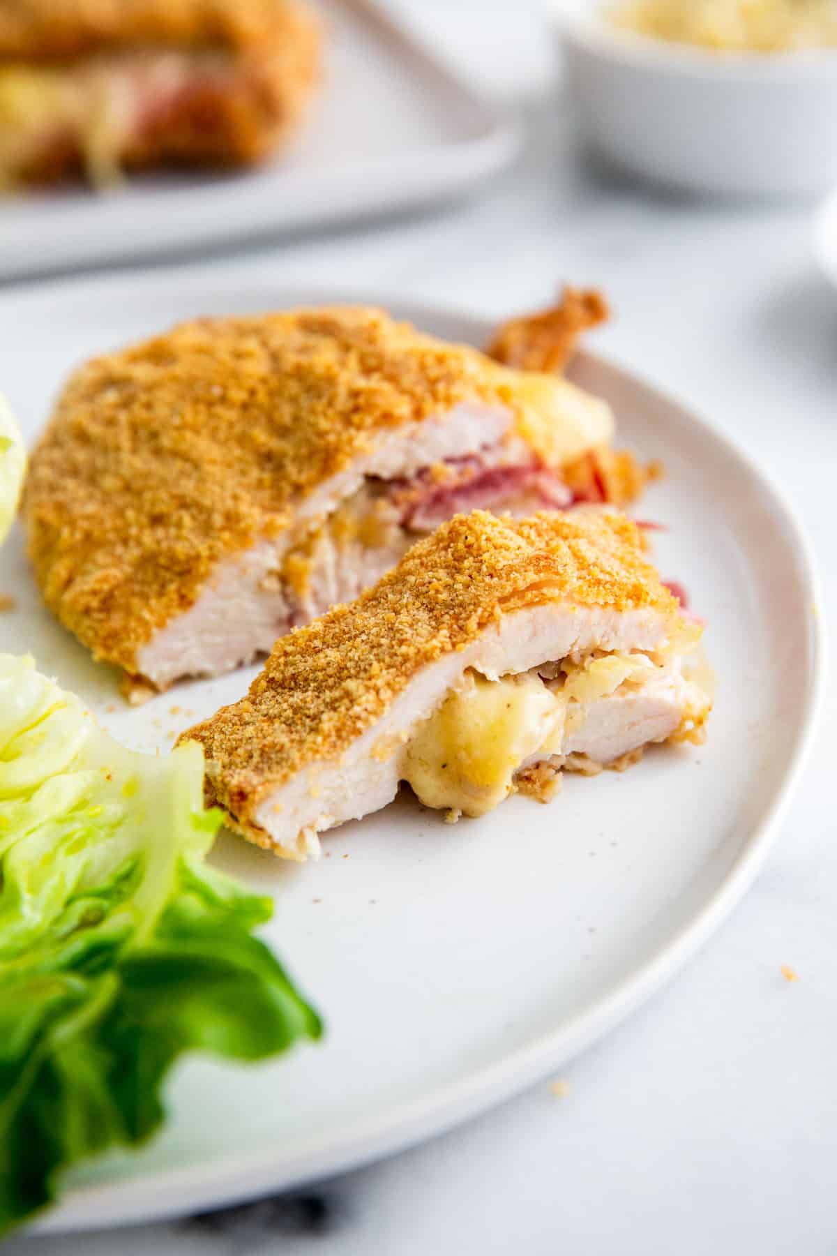 stuffed chicken on a white plate with a salad 