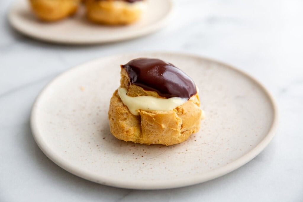 a gluten-free cream puff filled with pudding and topped with chocolate 