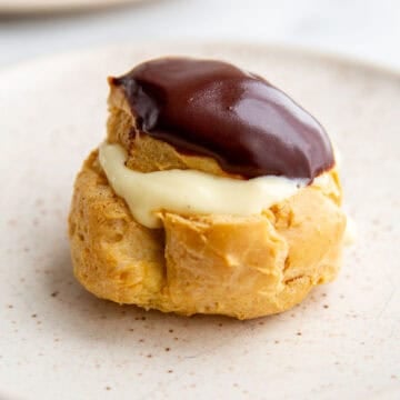 a gluten-free cream puff filled with pudding and topped with chocolate