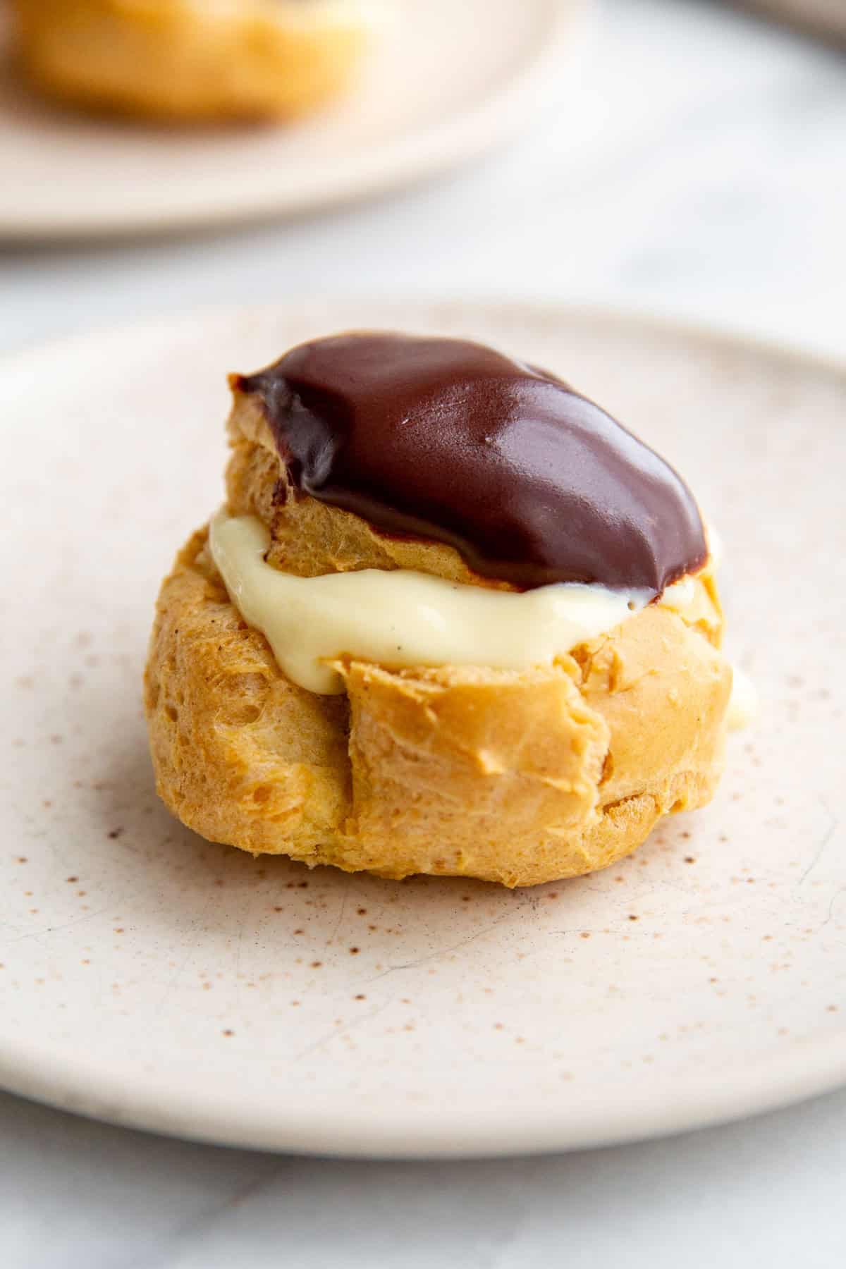 a gluten-free cream puff filled with pudding and topped with chocolate