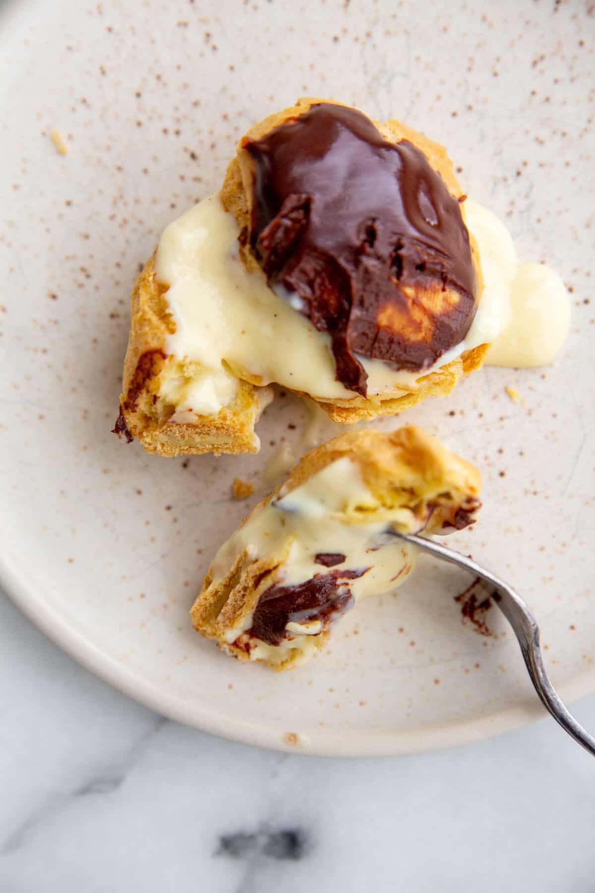 gluten-free cream puffs on a white plate with a fork