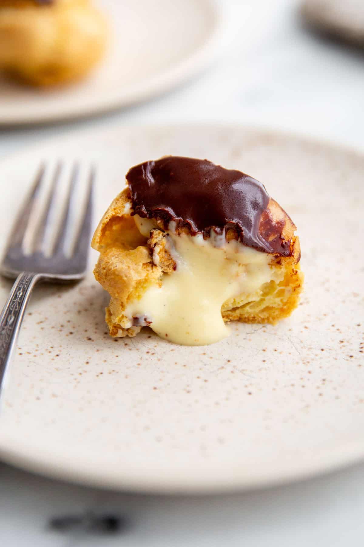 a gluten-free cream puff topped with chocolate and cut in the center to show the creamy filling