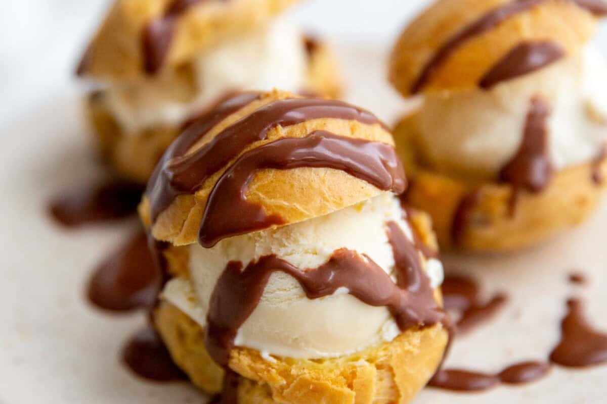 cream puff shells filled with ice cream and topped with chocolate 