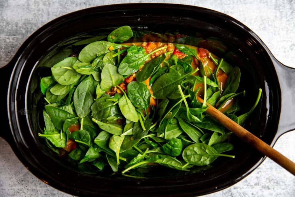 mixing fresh spinach into the stew