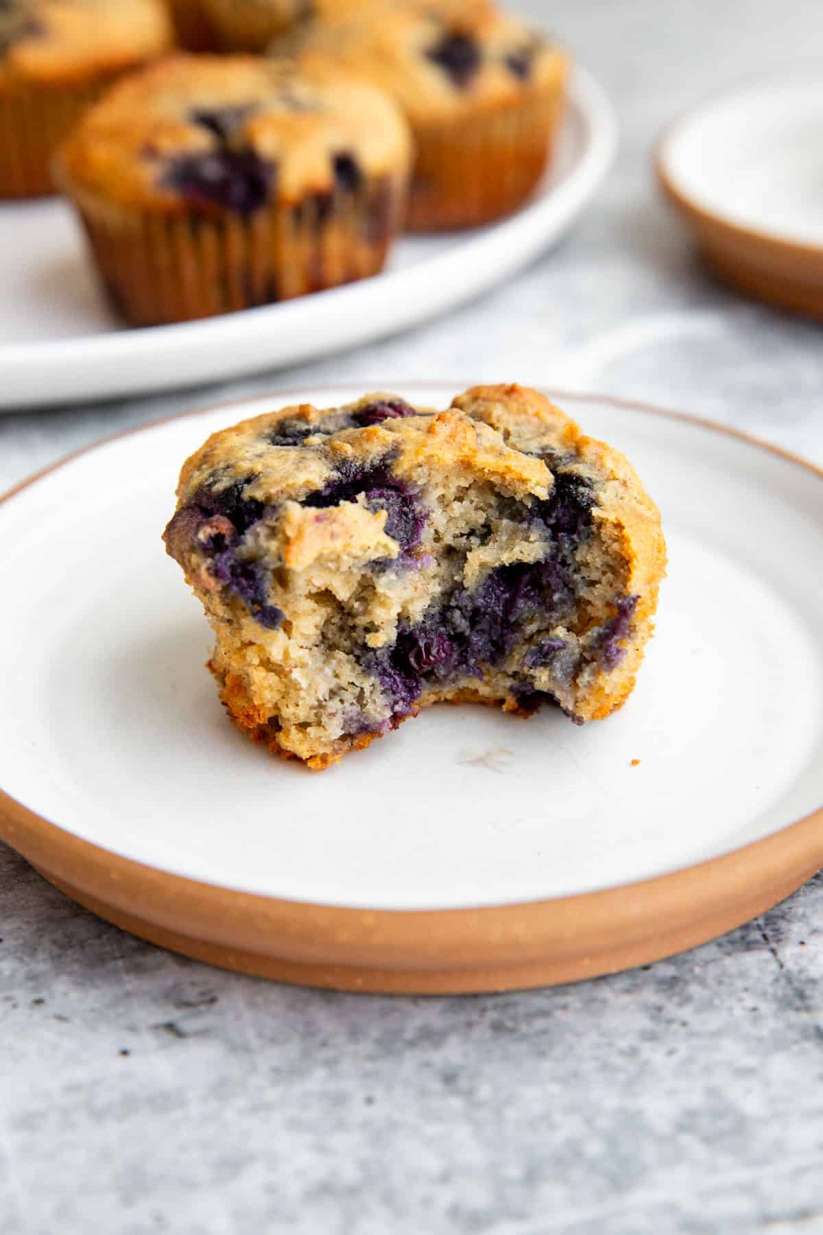 half of a muffin on a plate to show the fluffy, delicious center.