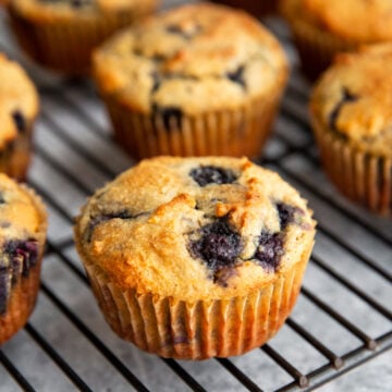 a gluten-free blueberry banana muffin on a wire cooling rack