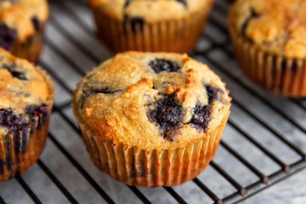 a close up of a fluffy gluten-free blueberry banana muffin on a cooling rack.