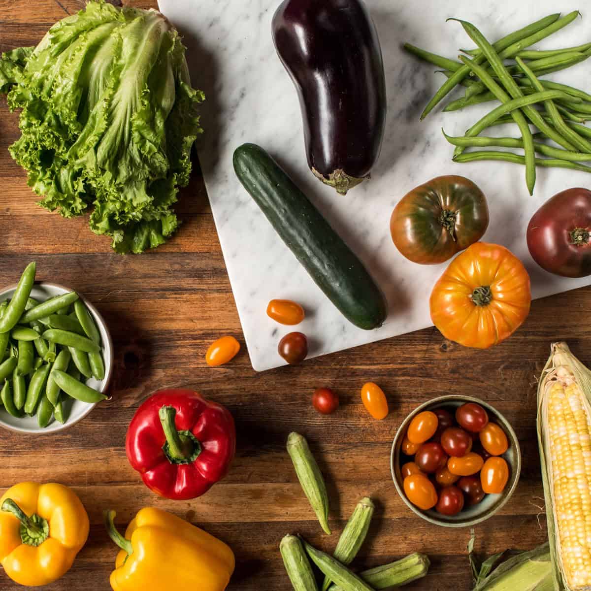 Fresh seasonal summer produce on a wooden cutting board.